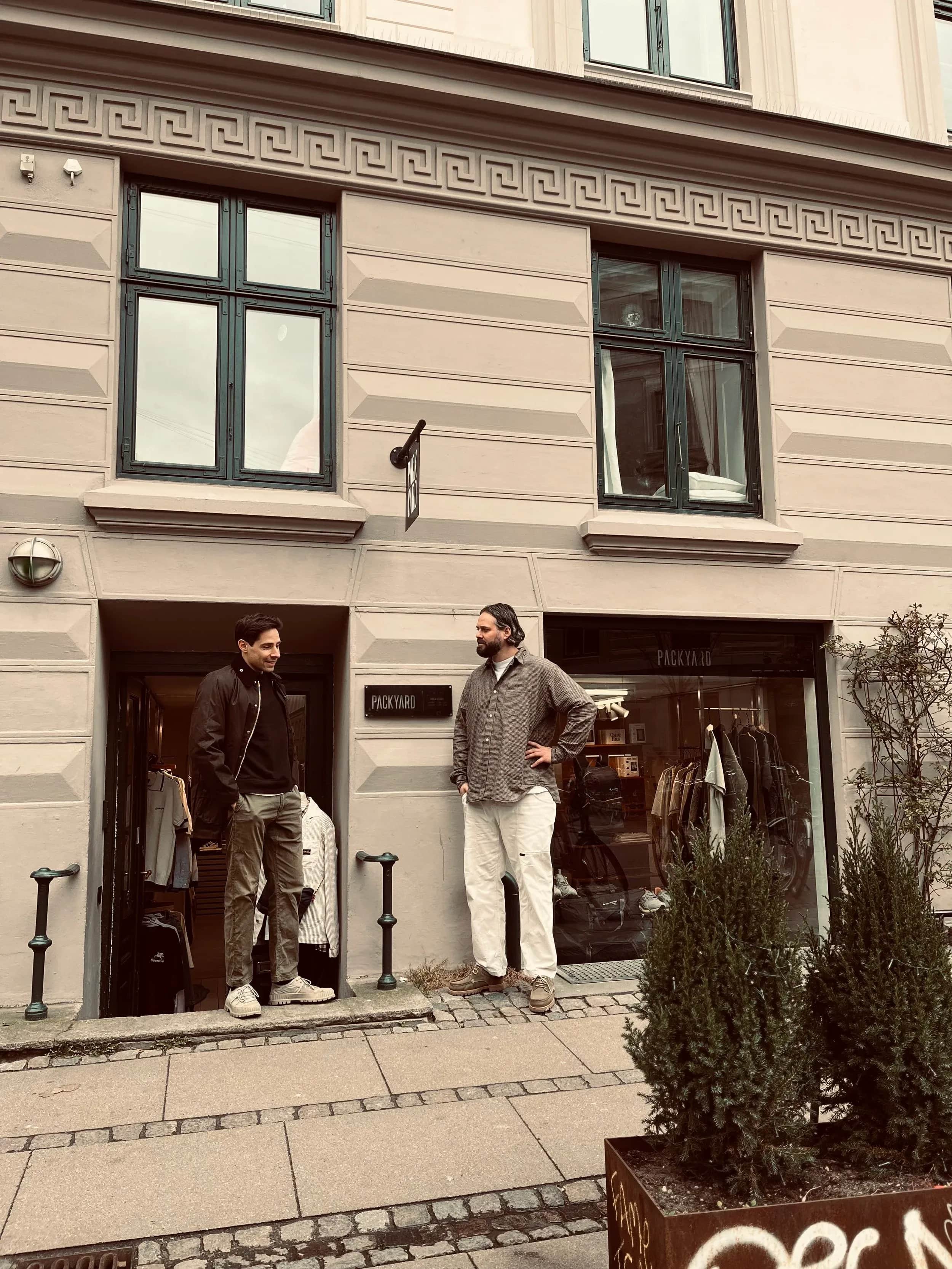Tre personer står foran en lys butiksfacade.