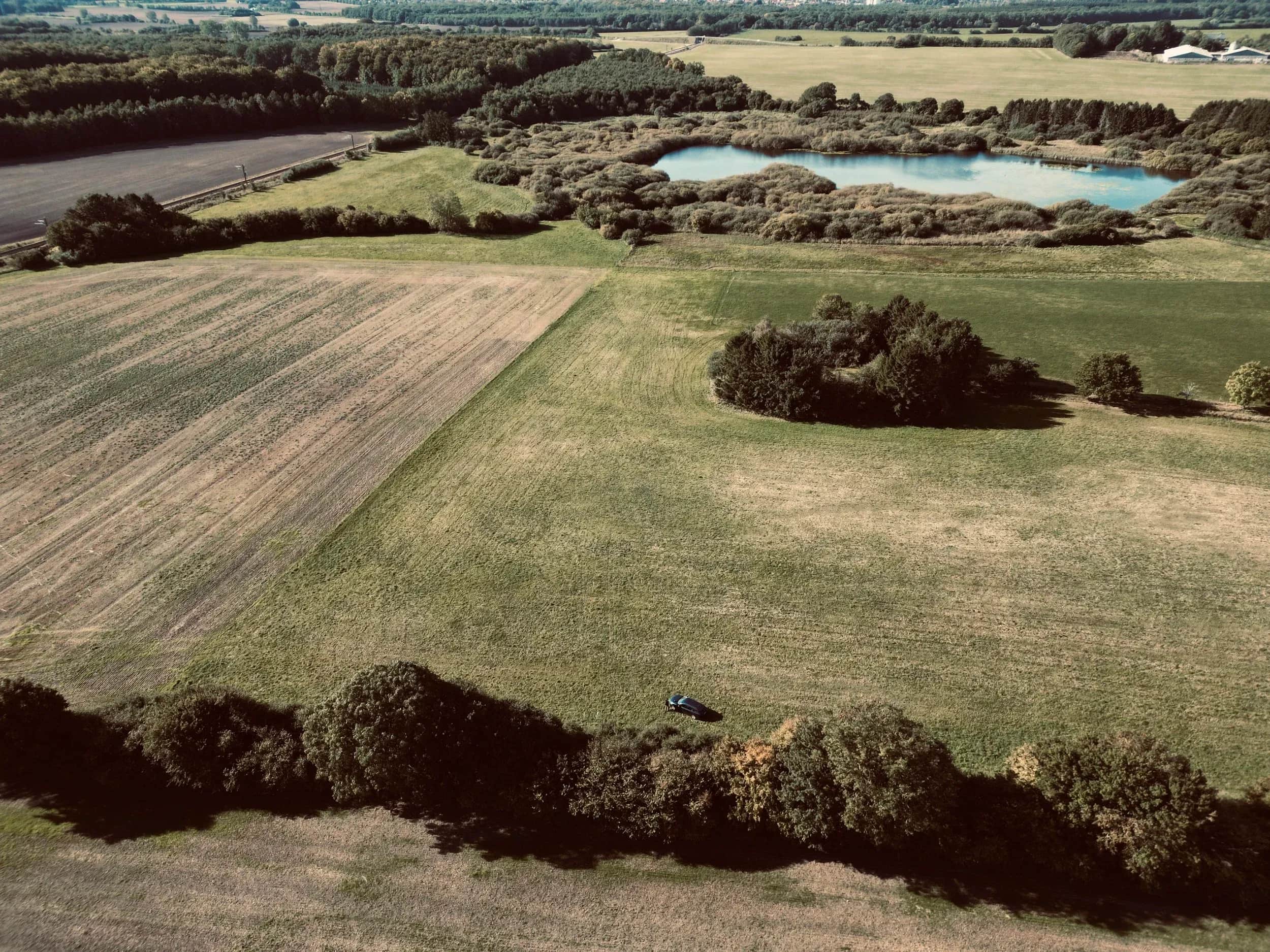 Luchtfoto van velden, groepjes bomen en twee kleine meertjes.